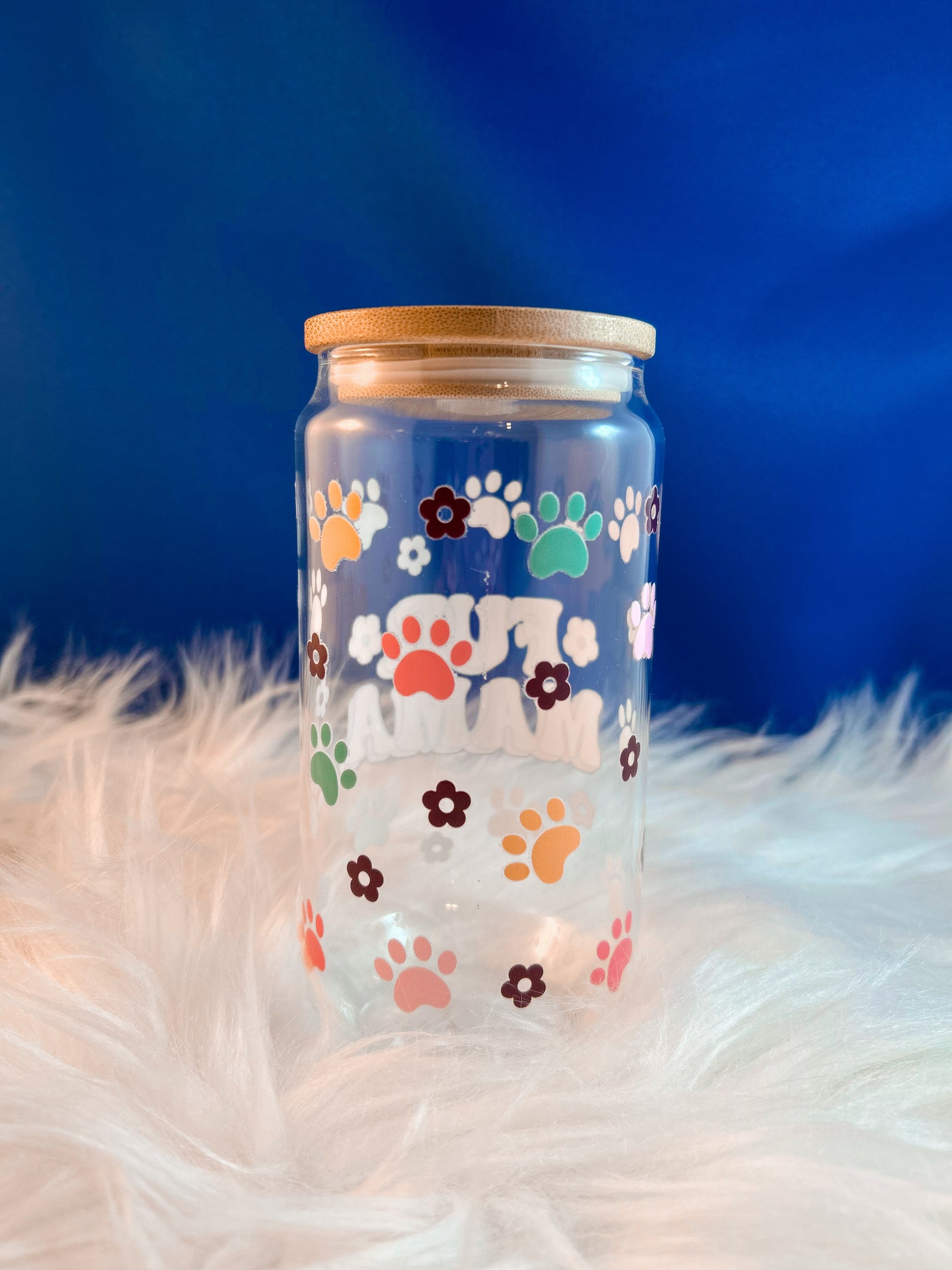 Clear glass jar with colorful paw prints on a fluffy white surface and blue background