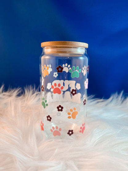 Clear glass jar with colorful paw prints on a fluffy white surface and blue background